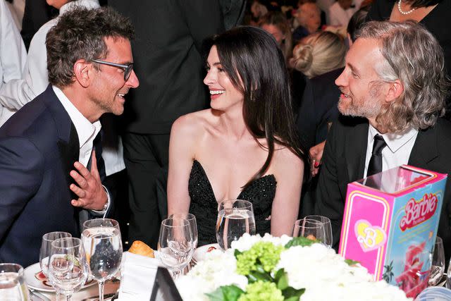 <p>Kevin Mazur/Getty</p> Bradley Cooper, Anne Hathaway, and Adam Shulman on January 11, 2024 in New York City.