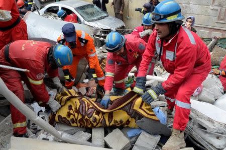 Firefighters carry the body of a victim who was killed after an air strike against Islamic State triggered a massive explosion in Mosul, Iraq, March 22, 2017. Picture taken March 22, 2017. REUTERS/Stringer