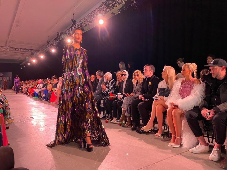 A model walks the runway in purple, sequined gown and cape during Naeem Khan's NYFW show.