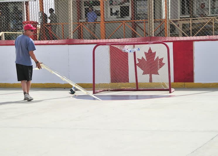 Corporal Ronald Gowers lifts tape from the newly painted goalie crease during the renovations of the hockey rink at Kandahar Airfield in this photo from August 2011. Photo from MCpl Dan Shouinard/Canadian Forces