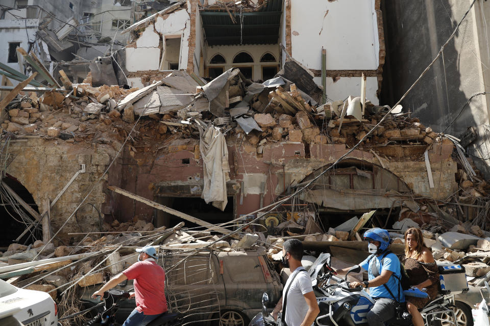 Citizens ride their scooters and motorcycles in front of a house that was destroyed in Tuesday's massive explosion in the seaport of Beirut, Lebanon, Wednesday, Aug. 5, 2020. (AP Photo/Hussein Malla)