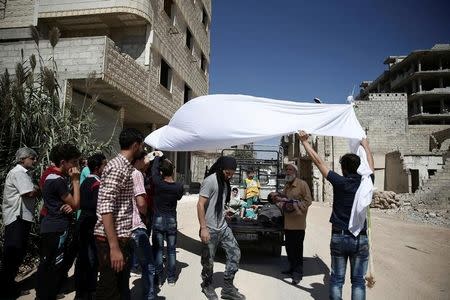 Men hold a white cloth over actors as they perform a scene in a film directed by Humam Husari in the rebel-held besieged town of Zamalka, in the Damascus suburbs, Syria September 19, 2016. REUTERS/Bassam Khabieh