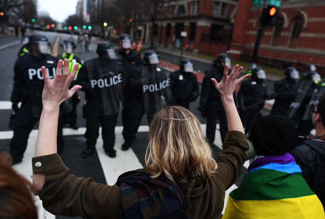 An anti-Trump protester holds her hands up as police officers lineup in Washington, DC,: JEWEL SAMAD/AFP/Getty Images