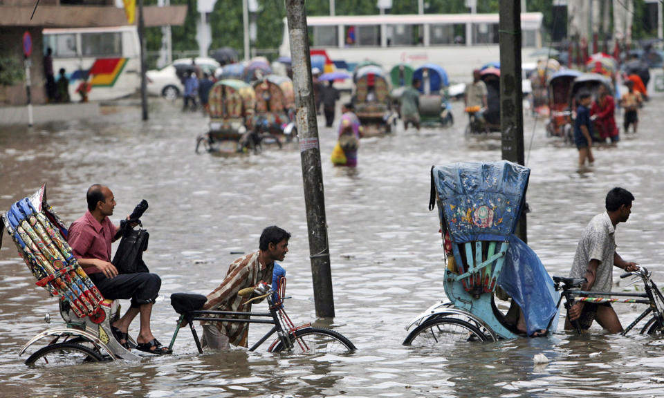 FILE - In this Tuesday, July 28, 2009 file photo, drivers pull their rickshaws carrying passengers through a flooded street in Dhaka, Bangladesh. Bangladesh plans to present its “climate prosperity plan” aimed at mitigating the effects of global warming on economic development at the forthcoming U.N. climate talks in Glasgow, Bangladeshi climate officer Abul Kalam Azad said in an interview with The Associated Press on Friday, Oct. 22, 2021. With most of its 160 million people tightly packed into low-lying areas along the Bay of Bengal, Bangladesh is considered especially prone to flooding, extreme weather and the loss of farmland to rising ocean levels. (AP Photo/Pavel Rahman, File)