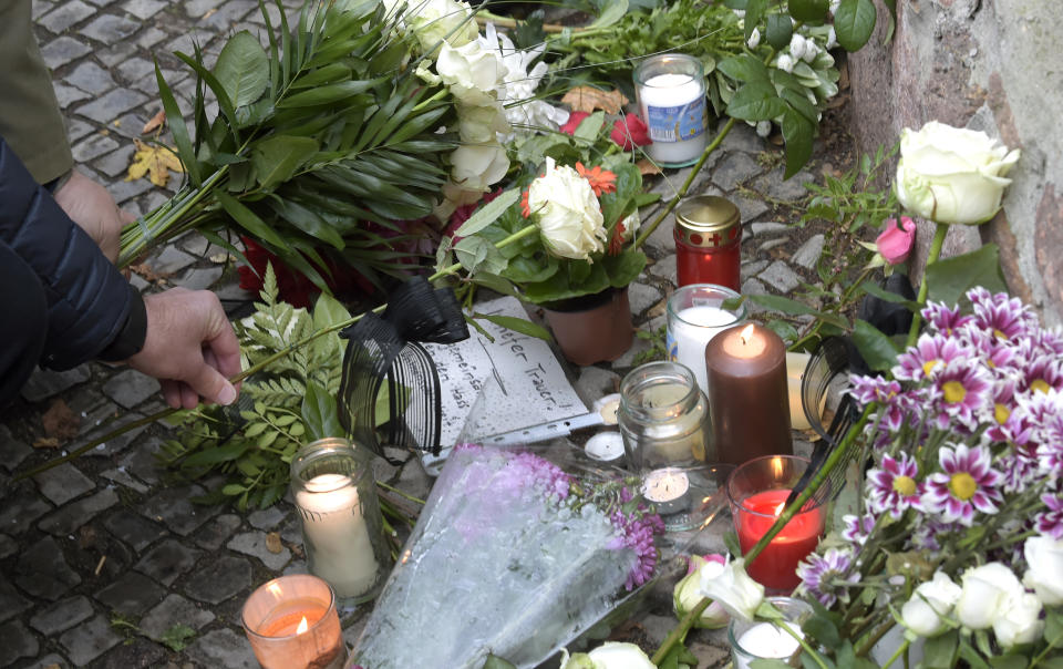 People place down flowers in front of a synagogue in Halle, Germany, Thursday, Oct. 10, 2019. A heavily armed assailant ranting about Jews tried to force his way into a synagogue in Germany on Yom Kippur, Judaism's holiest day, then shot two people to death nearby in an attack Wednesday that was livestreamed on a popular gaming site. (AP Photo/Jens Meyer)