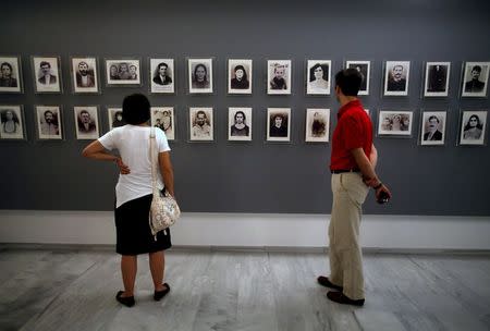 Visitors look at photos of victims in the "Nazi crimes" museum on the eve of the 68th anniversary of the "Distomo massacre", committed by the Nazis during World War Two, in the village of Distomo northwest of Athens in this June 9, 2012 file photo. REUTERS/Yannis Behrakis/Files