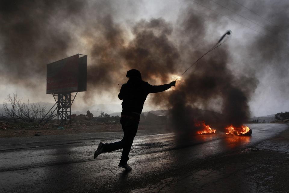 A Palestinian protester uses a sling to hurl a stone during clashes with Israeli troops at a protest near Ramallah