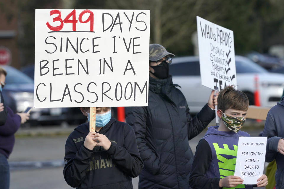 Students hold signs as they take part in a rally to encourage wider opening of in-person learning in the Issaquah School District, Wednesday, Feb. 24, 2021, in Issaquah, Wash., east of Seattle. Students in kindergarten and lower-elementary grades in the district recently returned to school under a hybrid in-person learning program, but older elementary, middle-, and high school students are still being taught remotely. (AP Photo/Ted S. Warren)