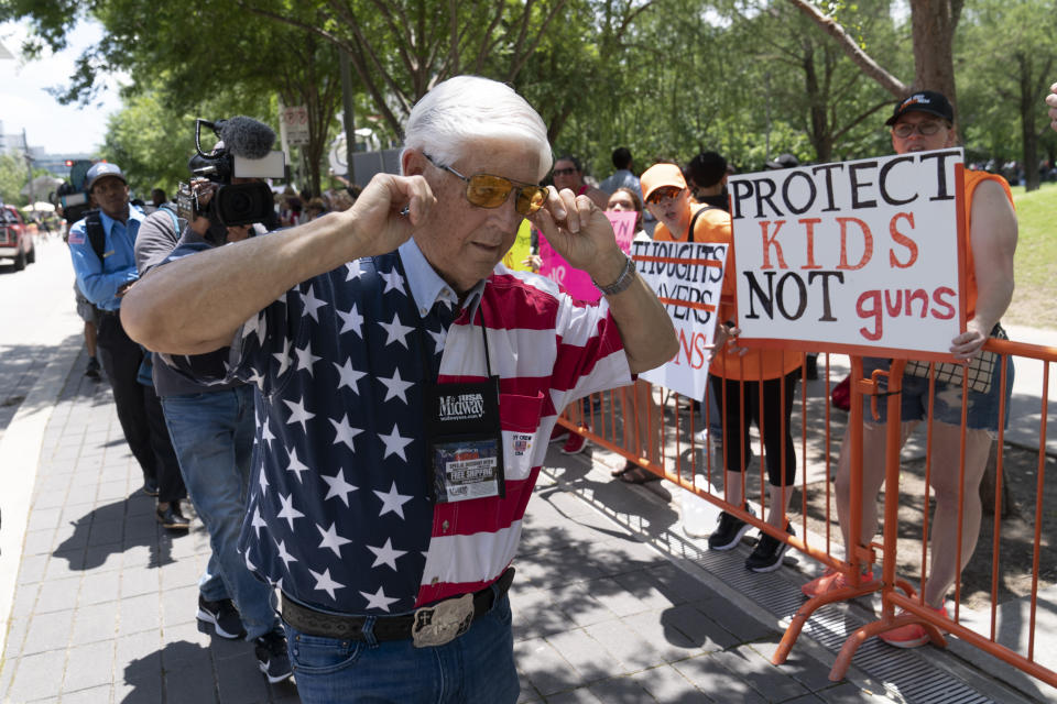 FILE - A member of the National Rifle Association plugs his ears with his fingers as he walks past protesters during the NRA Annual Meetings & Exhibits at the George R. Brown Convention Center, May 27, 2022, in Houston. Guns have long been a part of Texas culture — both in the state’s mythology and in reality. But to equate the number of guns with the number of people killed by guns strikes some as a false equivalence. (AP Photo/Jae C. Hong, File)