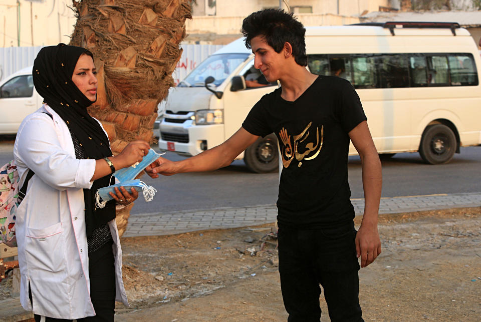 In this Tuesday, Sept. 18, 2018 photo, Hajar Youssif, an Iraqi activist and volunteer medic, who was kidnapped, beaten and threatened for attending protests, hands out masks to help protect against tear gas as protesters gather for a demonstration, in Basra, Iraq. Activists say powerful Iranian-backed militias that control Iraq’s oil capital of Basra have waged a campaign of intimidation and arbitrary arrests to silence protests aimed at poor government services and Tehran’s outsized influence in the region. (AP Photo/Nabil al-Jurani)