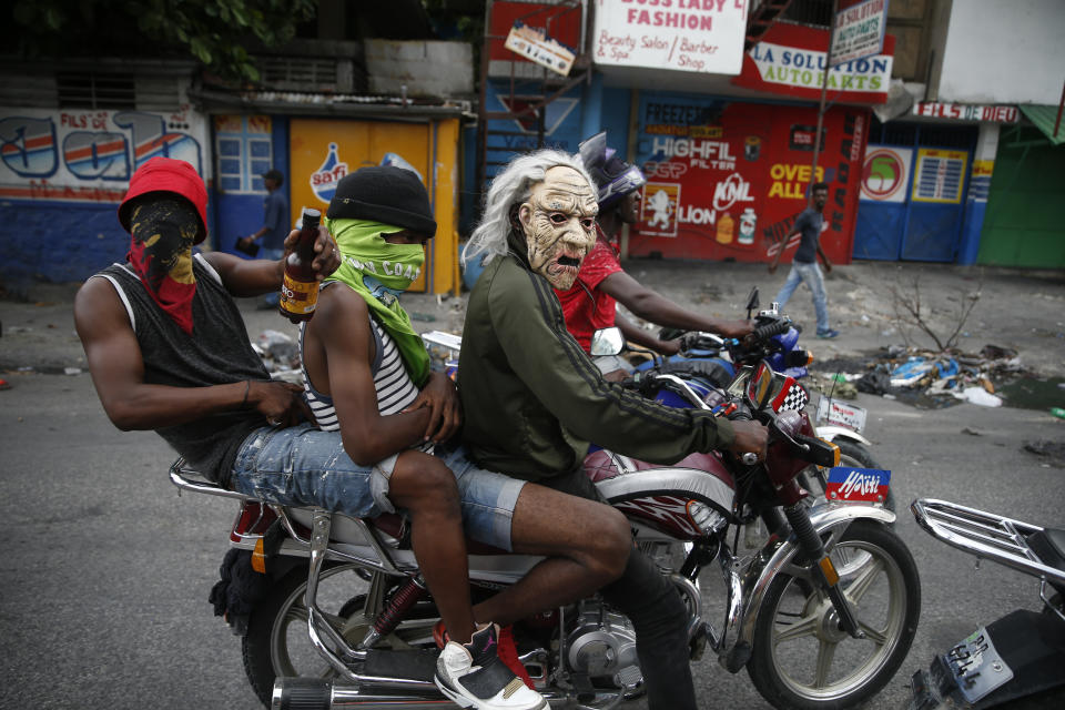 Masked protestors ride a motorcycle on Sept. 30, 2019, in Port-au-Prince, Haiti, where demonstrators set fires and called for Haiti's President Jovenel Moise to resign. (AP Photo/Rebecca Blackwell)