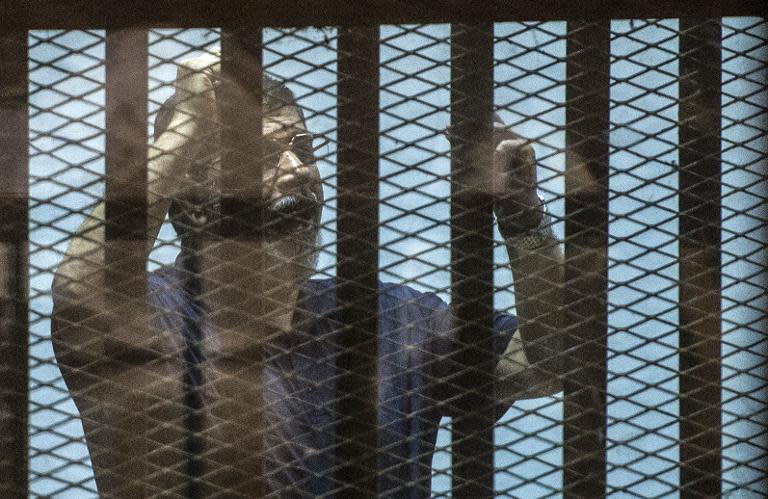 Ousted Egyptian president Mohamed Morsi, who was recently sentenced to death, gestures from inside the defendants' cage during his new trial in Cairo on May 23, 2015, with 25 other defendants including prominent Islamists and secular figures