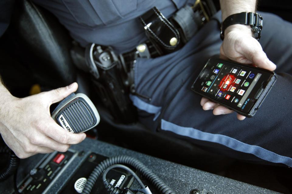 In a May 6, 2014 photo, Sgt. Andres Wells of the Kalamazoo Dept. of Public Safety, who successfully used text messaging to negotiate with a suicidal robbery suspect during a 2011 standoff is seen in his armored vehicle holding his cell phone and vehicle speaker. The suspect was unable to hear Wells's voice through the horn of the Bearcat armored car and gave up after a texting conversation with Sgt. Wells. With 6 billion text messages exchanged daily in the United States, texting is becoming a more frequent part of police crisis negotiations. (AP Photo/Mark Bugnaski)