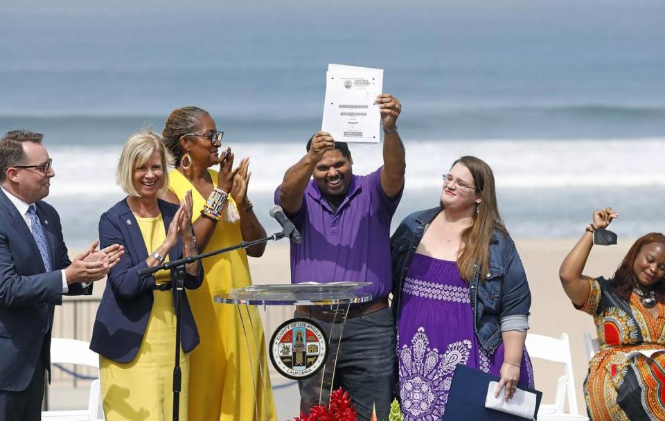 Anthony Bruce, center, holds up the property deed to Bruce’s Beach in 2022 as his wife, Sandra, second from right; Kavon Ward, with the Justice for Bruce’s Beach movement, far right; and state and county officials cheer. A unanimous bill passed by the California Legislature cleared the way for the property’s return to descendants of a Black couple that had been driven out of Manhattan Beach in the 1920s.