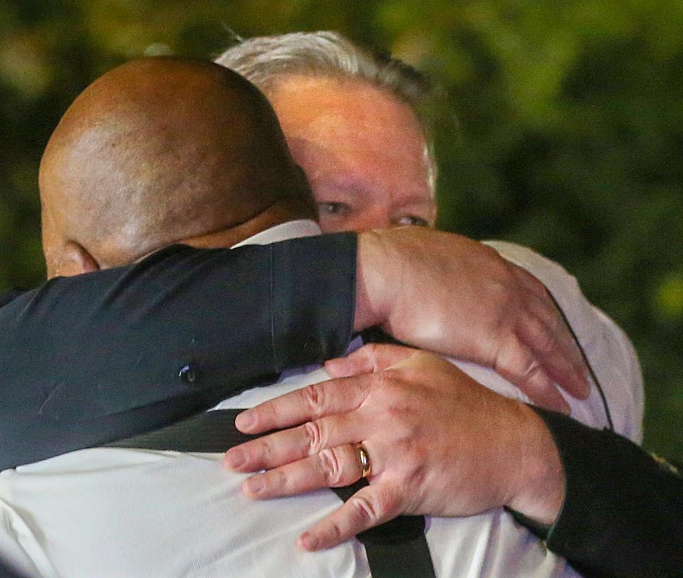 Pastor Lorenzo Glenn of the Macedonia Baptist Church, back to camera, hugs Police Chief Steve Mylett after a Friday night press conference outside Akron Children's Hospital.