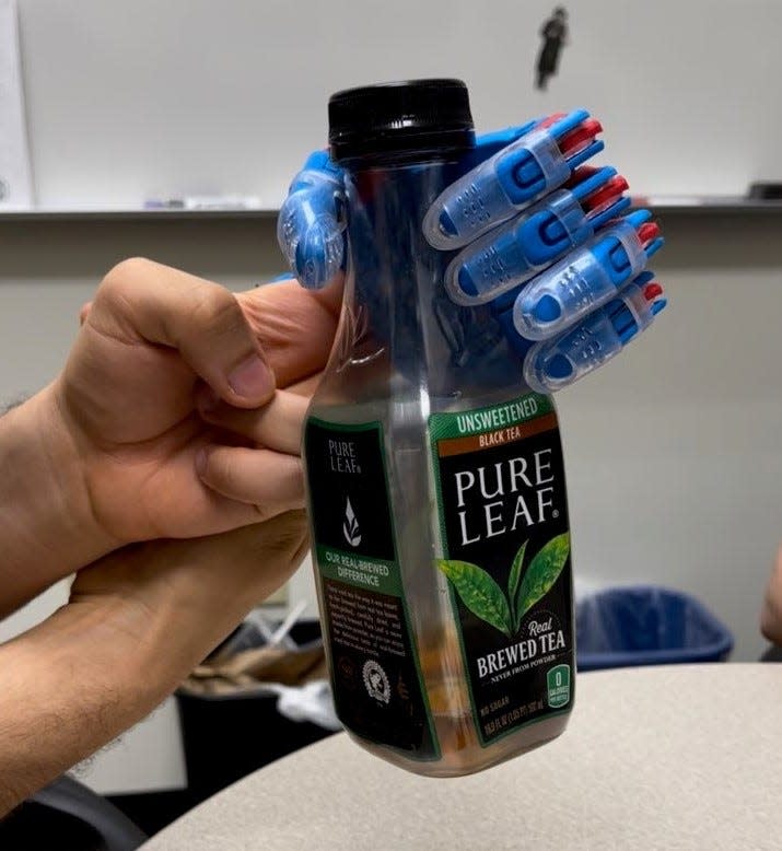 The prosthetic hand made by two Brookdale students grips an ice tea bottle.