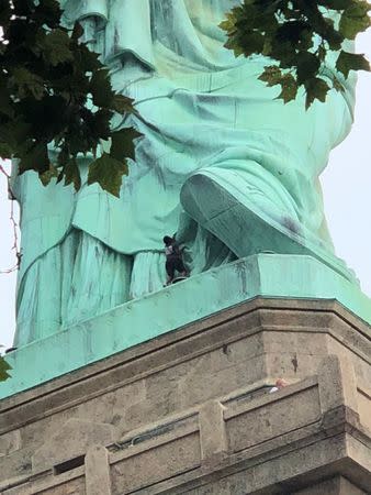 A protester is seen on the Statue of Liberty in New York, New York, U.S., July 4, 2018 in this picture obtained from social media. Danny Owens/via REUTERS