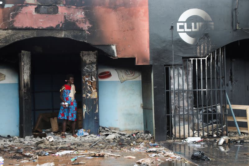 A woman stands near the rubble of a burnt store after post electoral inter-community clashes, in M'Batto