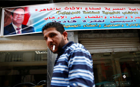 A man smokes ciggrate and walks near a abnner depicting Egypt's President Abdel Fattah al-Sisi that reads "We have chosen you for a second term" in Cairo, Egypt January 17, 2018. REUTERS/Amr Abdallah Dalsh