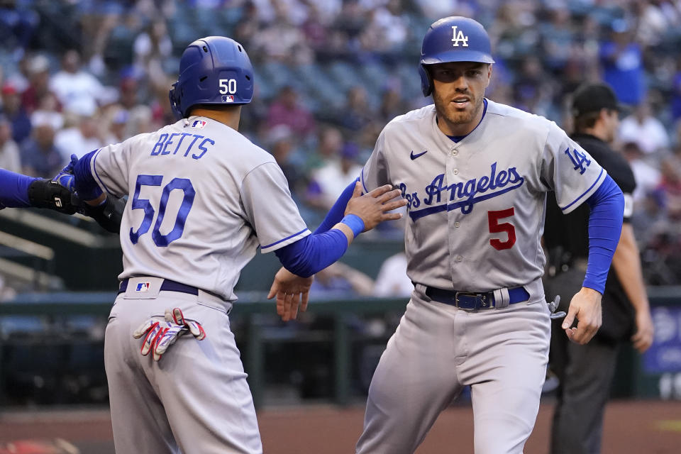 Los Angeles Dodgers' Freddie Freeman (5) and Mookie Betts (50) score on a double hit by Trea Turner during the first inning of a baseball game against the Arizona Diamondbacks, Monday, April 25, 2022, in Phoenix. (AP Photo/Matt York)