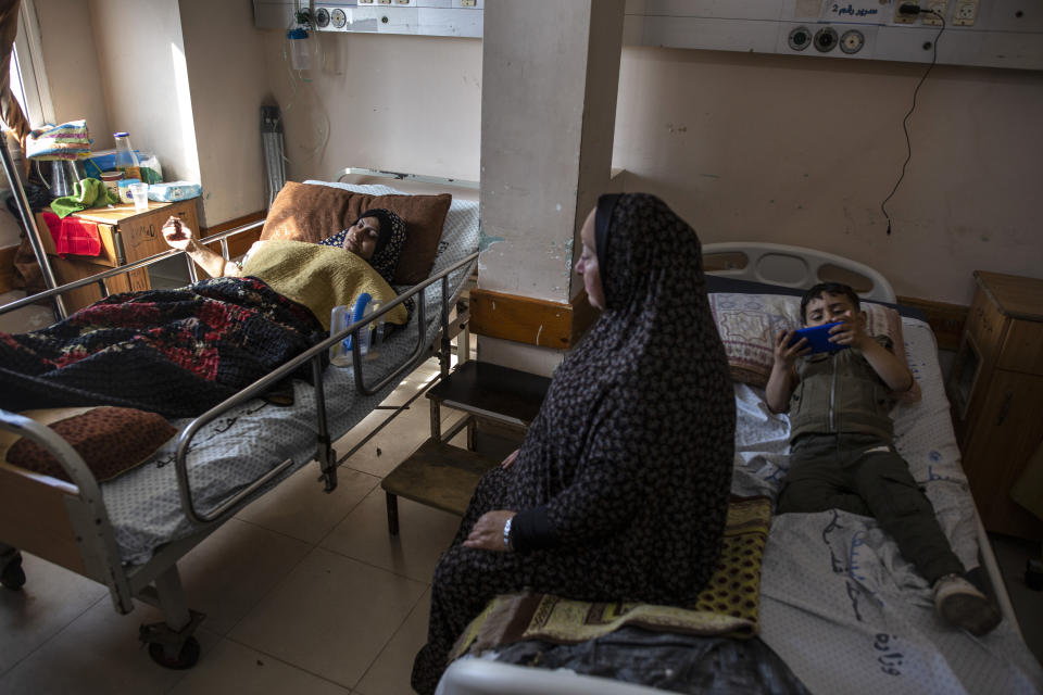 Ihsan Al-Masri, 24, left, rests at the Shifa hospital in Gaza City, May 13, 2021, as her son plays on a mobile phone on the bed next to her. Ihsan is receiving treatment for wounds caused by a May 10 Israeli strike that hit a nearby her family house in town of Beit Hanoun. Just weeks ago, the Gaza Strip’s feeble health care system was struggling with a runaway surge of coronavirus cases. Now doctors across the crowded coastal enclave are trying to keep up with a very different crisis: blast and shrapnel wounds, cuts and amputations. (AP Photo/Khalil Hamra)