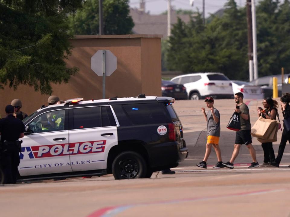 People walking in line with hands up next to an Allen, Texas, police cruiser.