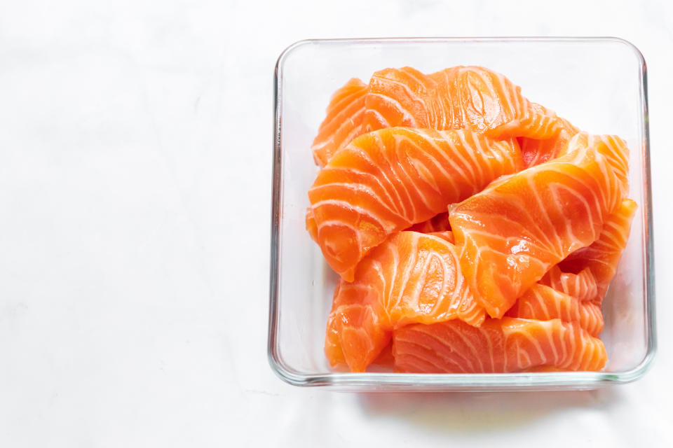 Fresh salmon slice in glass bowl. Top view isolated on white background.