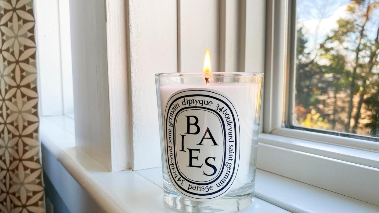 lit baies diptyque candle on window sill
