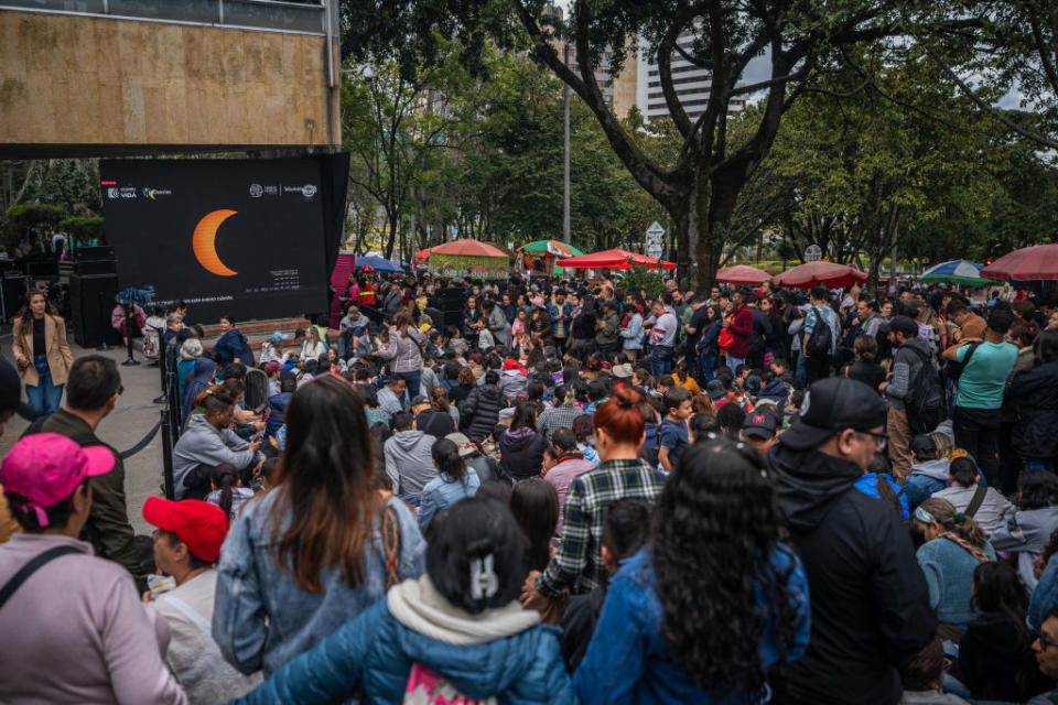 people watch the eclipse on a large screen.