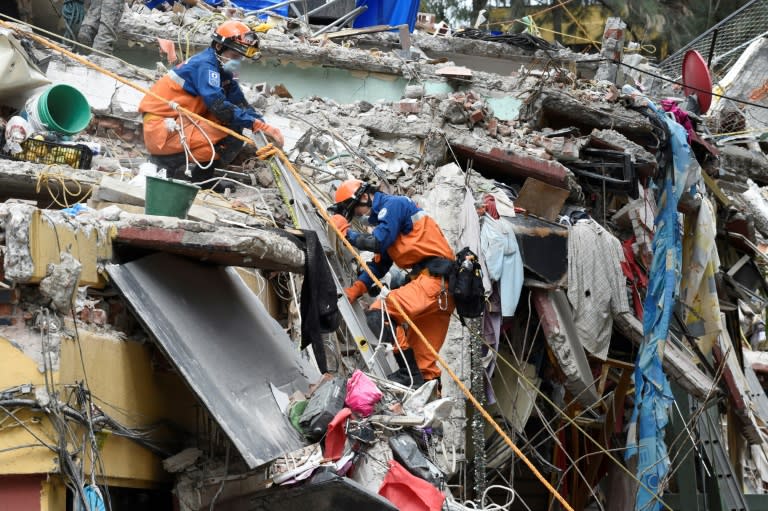 Rescue workers climb a building destroyed by the earthquake in Mexico City