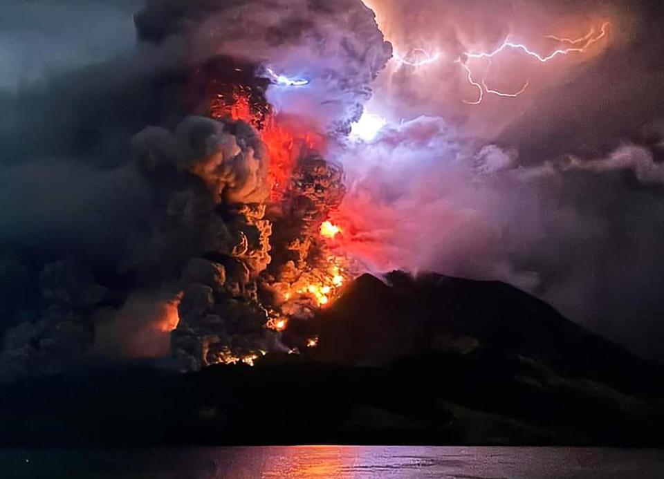 This handout photograph taken and released by the Center for Volcanology and Geological Hazard Mitigation on April 17, 2024, shows Mount Ruang spewing hot lava and smoke as seen from Sitaro, North Sulawesi. A volcano erupted several times in Indonesia's outermost region overnight on April 17, forcing hundreds of people to be evacuated after it spewed lava and a column of smoke more than a mile into the sky.