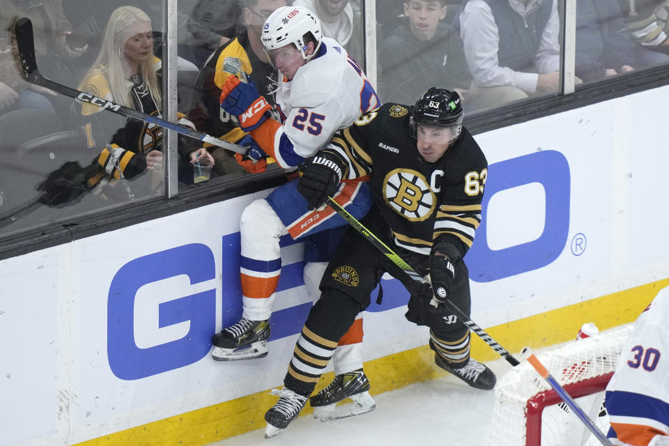 New York Islanders defenseman Sebastian Aho (25) and Boston Bruins left wing Brad Marchand (63) slam into the boards after colliding in the second period of an NHL hockey game, Thursday, Nov. 9, 2023, in Boston. (AP Photo/Steven Senne)