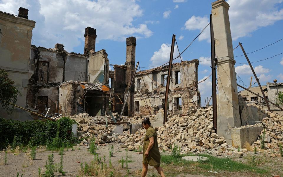 A local resident walks near the ruins of a destroyed apartment building - Reuters