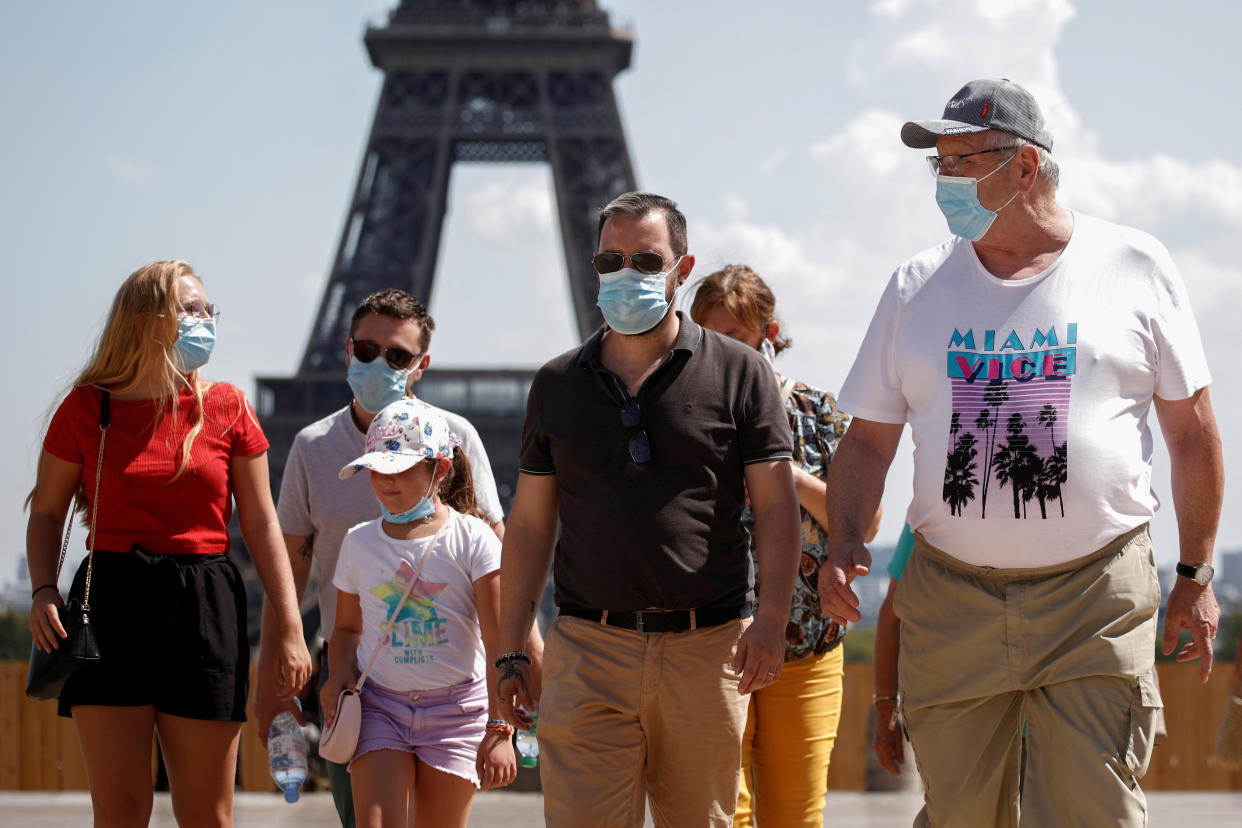 People wearing protective face masks walk at the Trocadero square near the Eiffel Tower in Paris as France reinforces mask-wearing as part of efforts to curb a resurgence of the coronavirus disease (COVID-19) across the country, August 9, 2020. REUTERS/Benoit Tessier