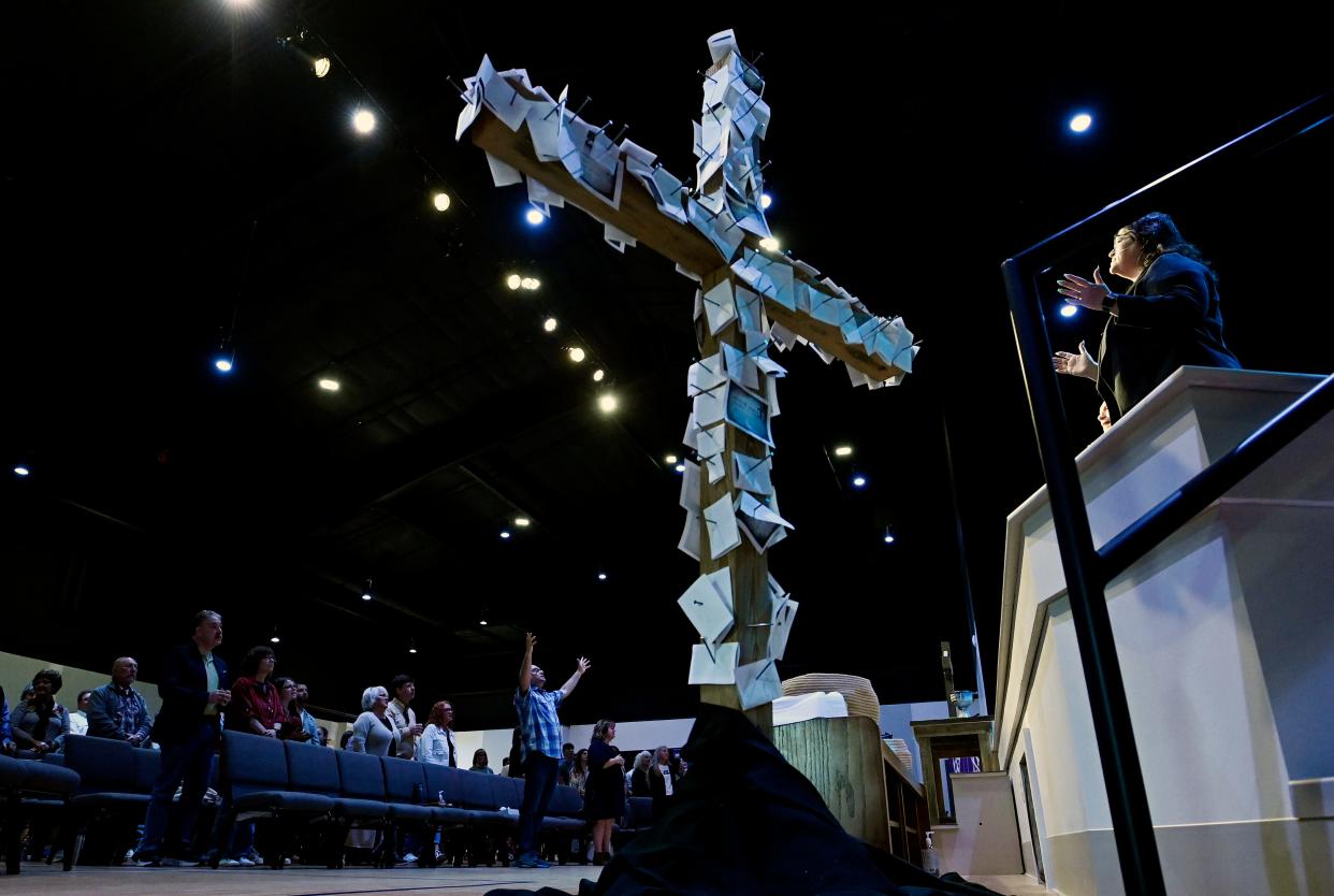 Lead Pastor Daron Brown, bottom center, raises his arms in praise as Candy Lee, right, sings with the congregation during Palm Sunday service at Waverly Church of the Nazarene on Sunday, March 24, 2024, in Waverly, Tenn. Congregation members’ spiritual notes are nailed to a cross. The church’s original building on East Main Street was flooded during torrential flash flood that killed 20 people in 2021.