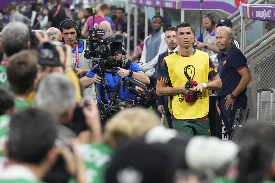 Photographers crowd around as Portugal's Cristiano Ronaldo arrives to take his seat on the bench prior the start of the World Cup round of 16 soccer match between Portugal and Switzerland, at the Lusail Stadium in Lusail, Qatar, on Tuesday, Dec. 6, 2022. (AP Photo/Pavel Golovkin)