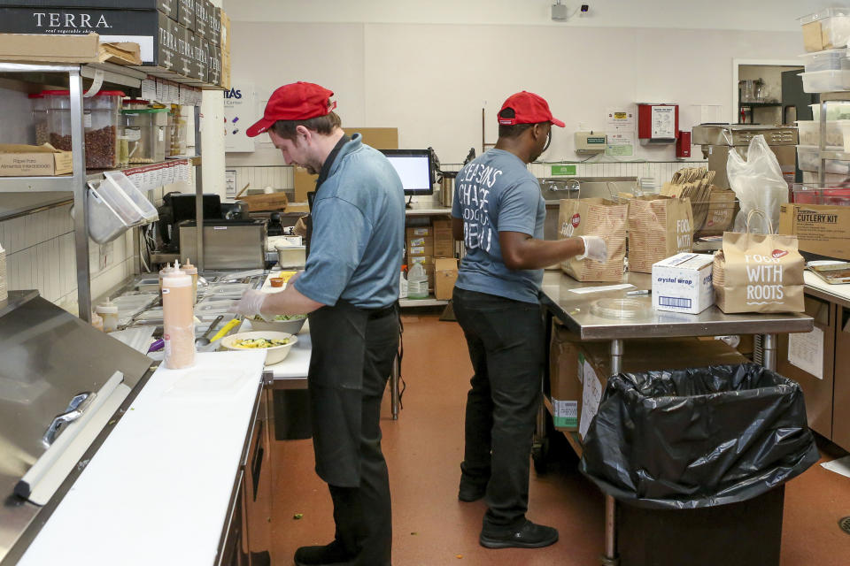 William Burns, left, general manager of the B.Good ghost kitchen inside Kitchen United's Chicago, Ill., location prepares food for delivery on Aug. 29, 2019. Kitchen United, a start-up that builds kitchen commissaries for restaurants looking to enter new markets through delivery or take-out only, has plans to open 40 more kitchens in cities across the U.S. through 2020. (AP Photo/Teresa Crawford)