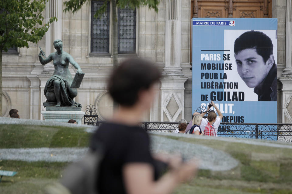 FILE - A picture of Israeli soldier Gilad Schalit is displayed at the Paris Town hall, June 25, 2011, to mark the 5th anniversary of his snatching by Palestinian militants. Hamas' 2006 seizure of Shalit consumed Israeli society for years — a national obsession that prompted Israel to heavily bombard the Gaza Strip and ultimately release over 1,000 Palestinian prisoners, many of whom had been convicted of deadly attacks on Israelis, in exchange for Shalit’s freedom. This time, Gaza’s Hamas rulers have abducted dozens of Israeli civilians and soldiers as part of a multipronged, shock attack. (AP Photo/Thibault Camus, File)