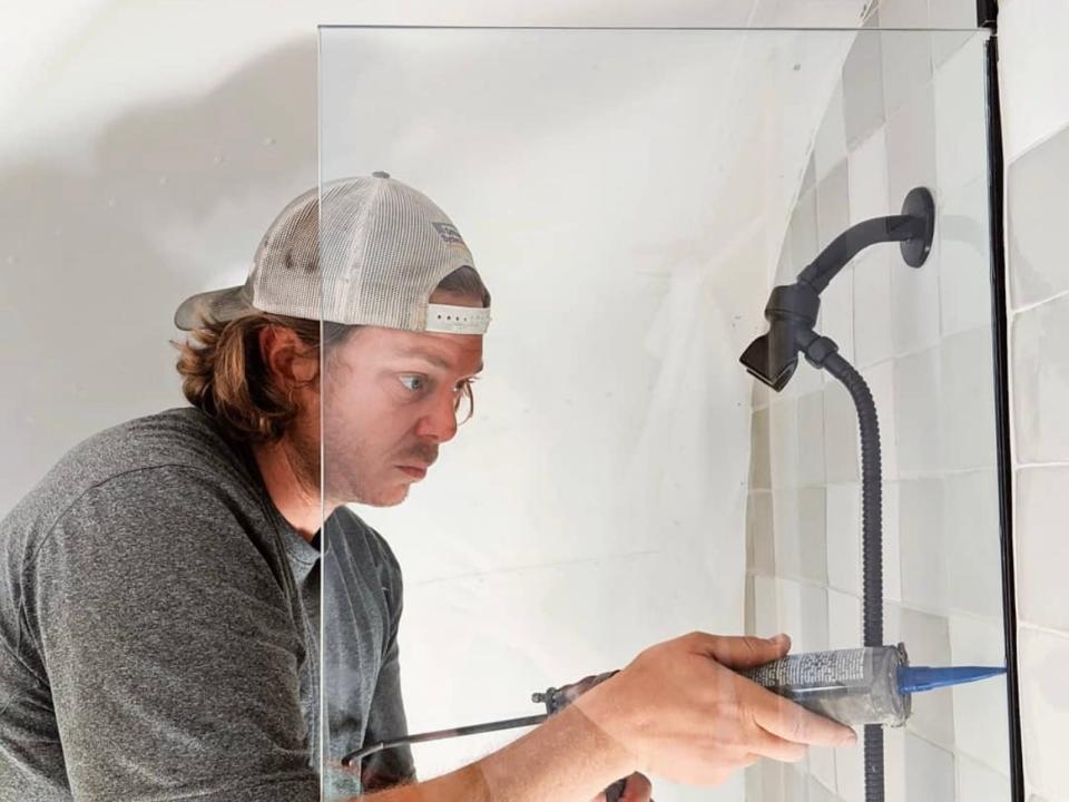 Suttles installing a glass shower divider in the bathroom.