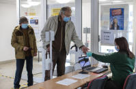 Lithuanian's, wearing face masks to protect against coronavirus, arrive to cast their ballots at a polling station during the second round of a parliamentary election in Vilnius, Lithuania, Sunday, Oct. 25, 2020. Polls opened Sunday for the run-off of national election in Lithuania, where the vote is expected to bring about a change of government following the first round, held on Oct. 11, which gave the three opposition, center-right parties a combined lead. (AP Photo/Mindaugas Kulbis)