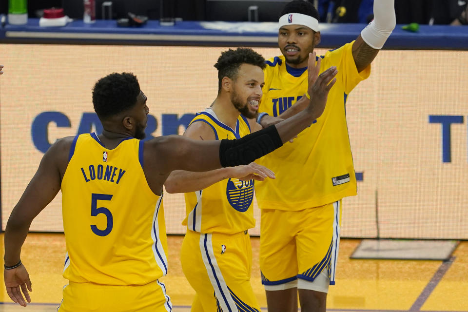 Golden State Warriors guard Stephen Curry, center, is congratulated by forwards Kevon Looney (5) and Kent Bazemore after scoring against the Sacramento Kings during the first half of an NBA basketball game in San Francisco, Monday, Jan. 4, 2021. (AP Photo/Jeff Chiu)