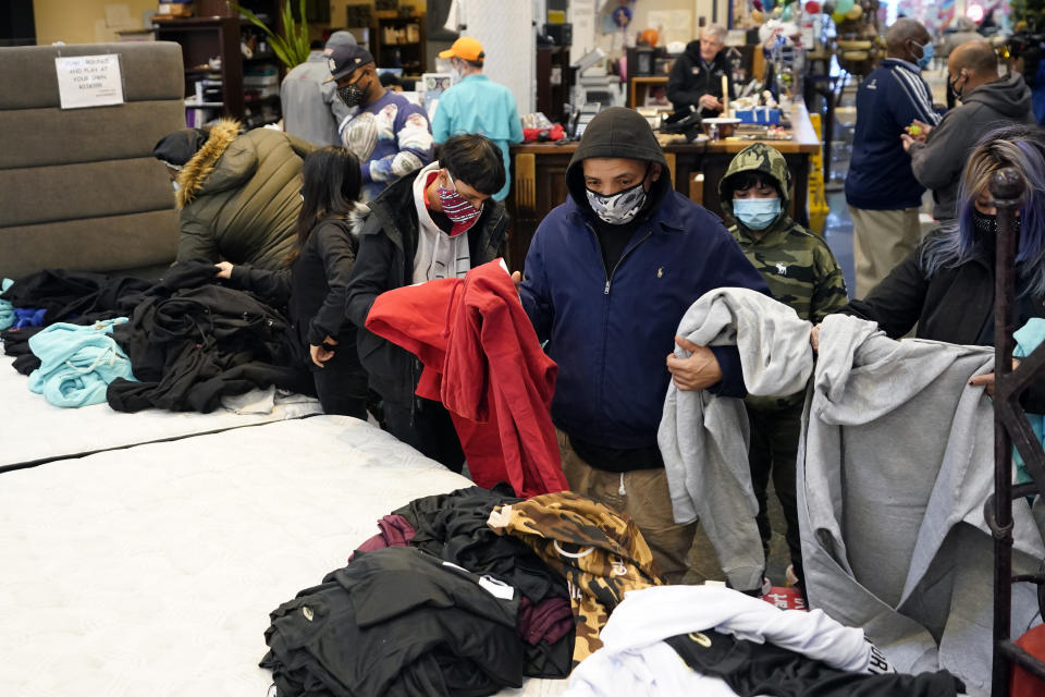 People select shirts and sweatshirts being given away at a Gallery Furniture store after the owner opened his business as a shelter for those without power at their homes Tuesday, Feb. 16, 2021, in Houston. More than 4 million people in Texas still had no power a full day after historic snowfall and single-digit temperatures created a surge of demand for electricity to warm up homes unaccustomed to such extreme lows, buckling the state's power grid and causing widespread blackouts. (AP Photo/David J. Phillip)