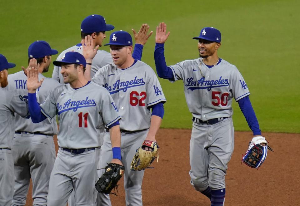 Dodgers center fielder Mookie Betts, right, celebrates with teammates after making the game-saving catch in a 2-0 win over the Padres on Saturday night.