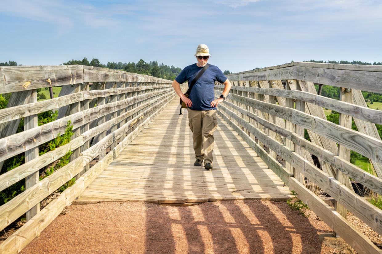 person walking on cowboy recreation and nature trail bridge in nebraska