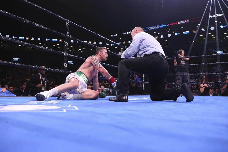 Ireland's Dennis Hogan receives a count during the seventh round of his WBC middleweight boxing match against Jermall Charlo on Saturday, Dec. 7, 2019, in New York. (AP Photo/Michael Owens)