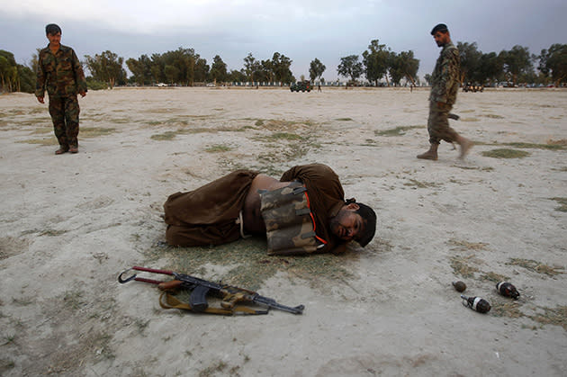 Afghan soldiers watch over a suicide bomber in Jalalabad on Sunday. Grenades and a gun are in the foreground, out of the bomber's reach. (Parwiz/Reuters)