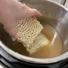 ramen noodles going into the broth