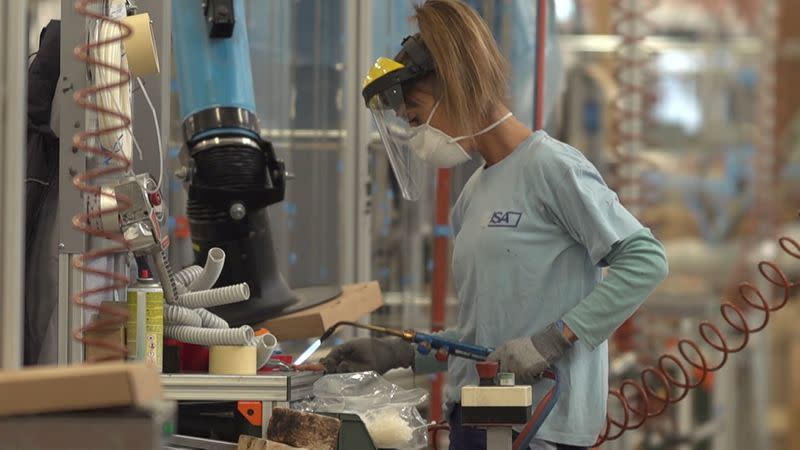 A worker, wearing a mask, uses a blowtorch inside the ISA factory in Bastia Umbra