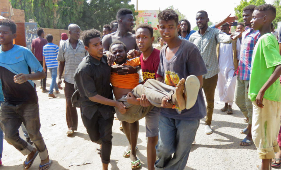 Sudanese carry a man injured during clashes as part of protests against a military coup that overthrew the transition to civilian rule. Source: Getty