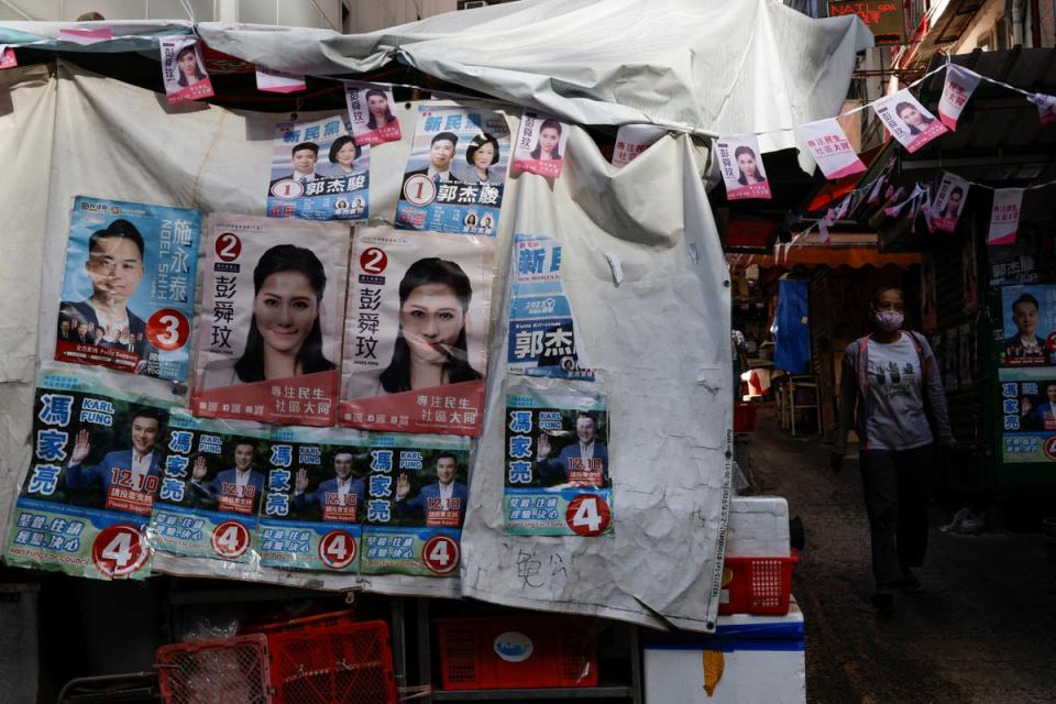 A woman walks past a stall with campaign posters of the District Council election candidates, in Hong Kong (Reuters)